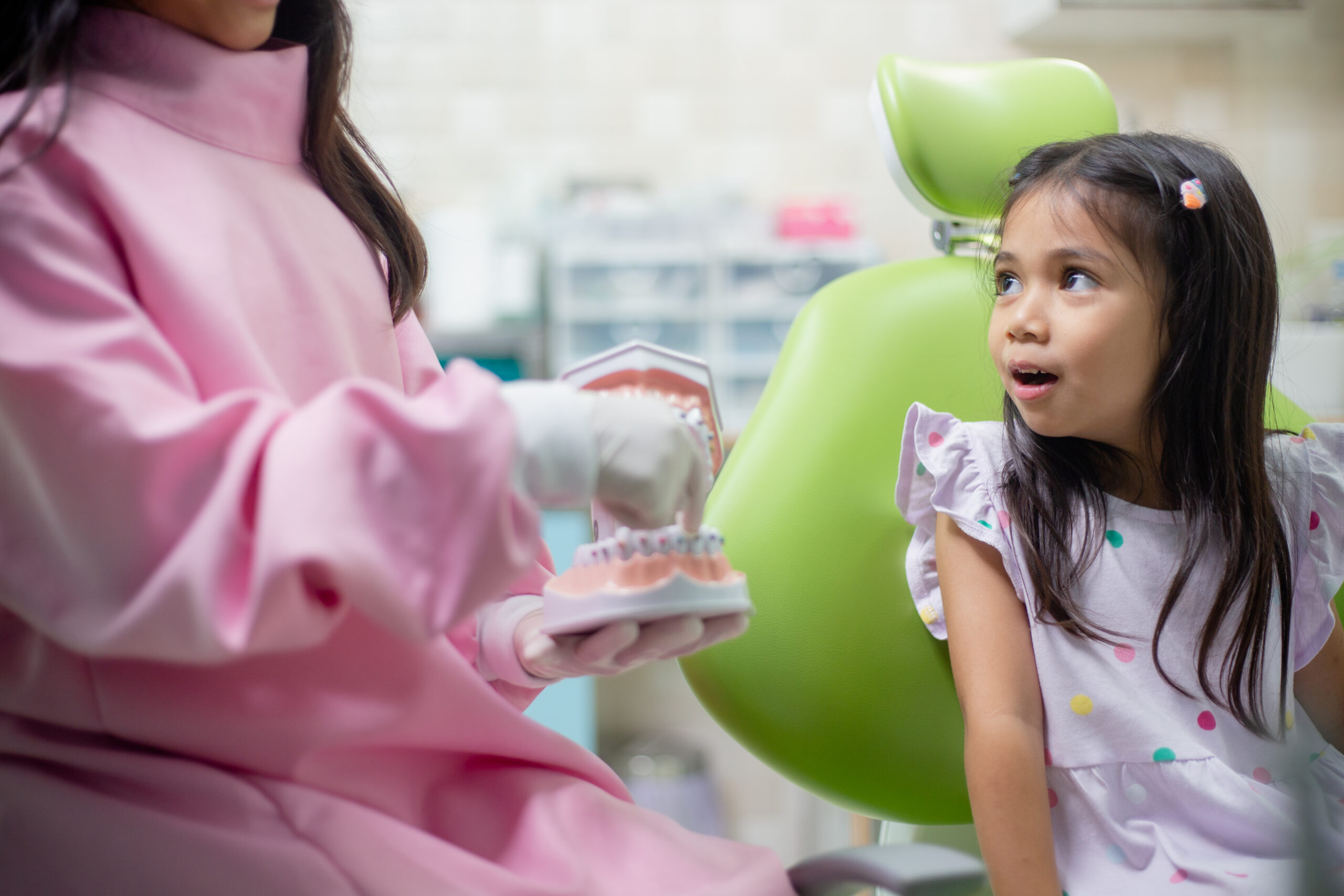 Pediatric dentist explaining braces treatment to a young child during a comfortable orthodontic visit