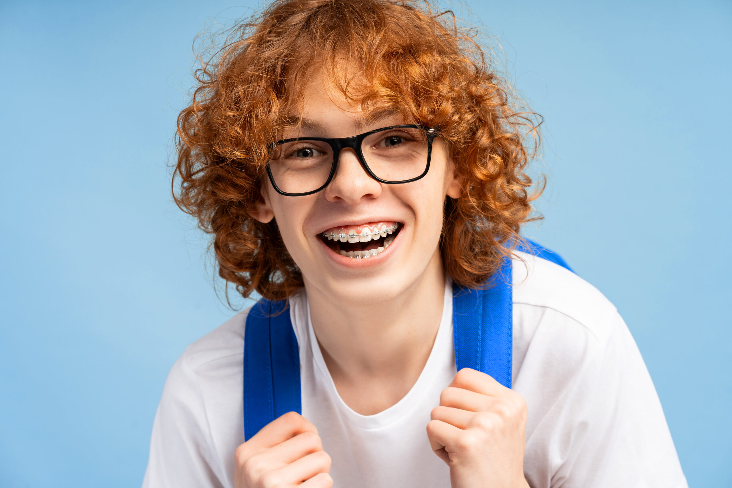 School-going child smiling with braces and backpack, showing a confident smile during orthodontic treatment