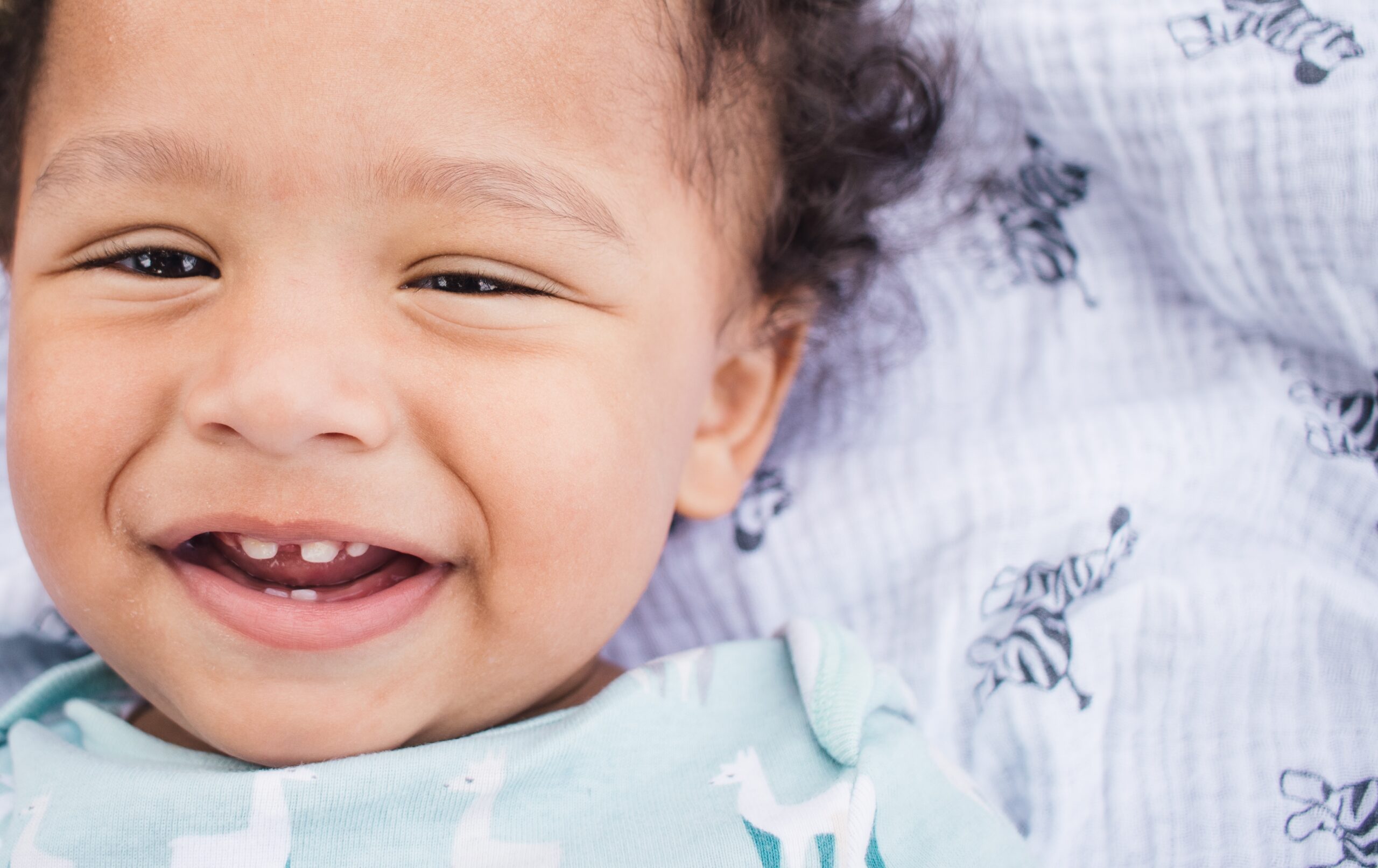 Smiling baby showing early baby teeth during a happy close-up moment