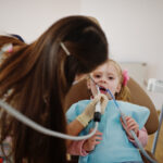 Pediatric dentist gently examining a young child’s teeth during a dental visit in a calm, child-friendly clinic setting
