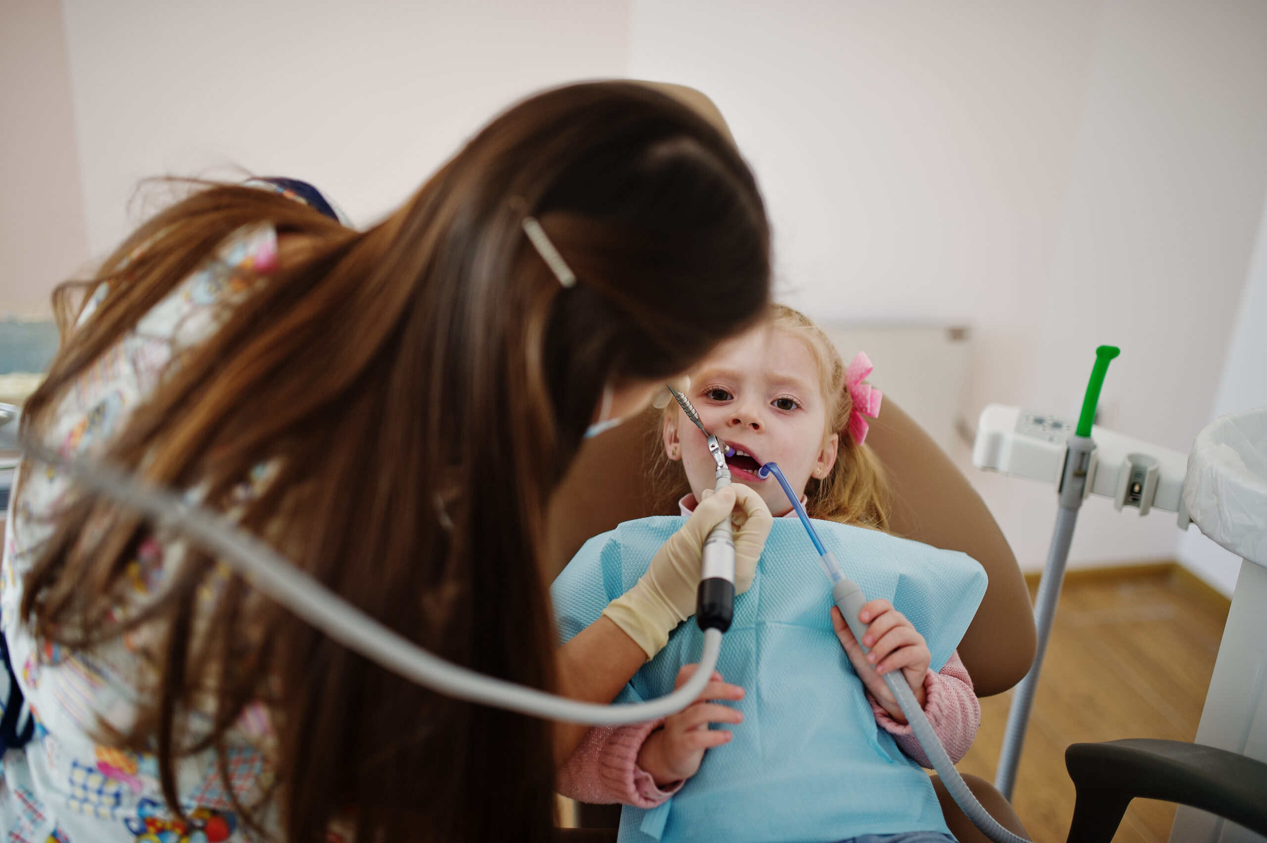 Pediatric dentist gently examining a young child’s teeth during a dental visit in a calm, child-friendly clinic setting