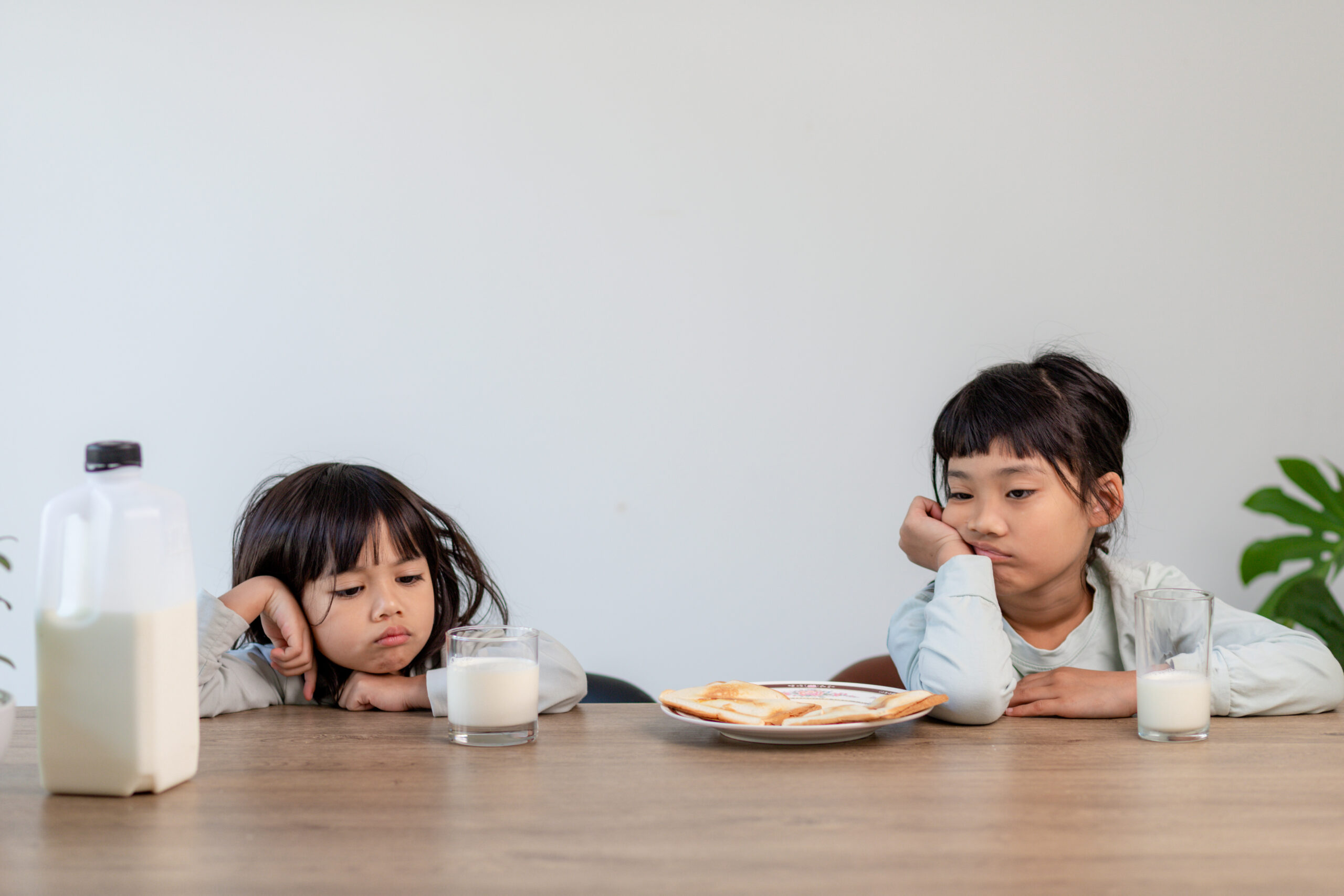 Child refusing to eat due to tooth pain, sitting at table with food and milk, showing discomfort during mealtime