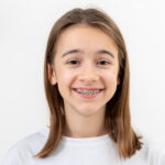 Child smiling with braces, showing clean teeth and healthy oral hygiene during orthodontic treatment